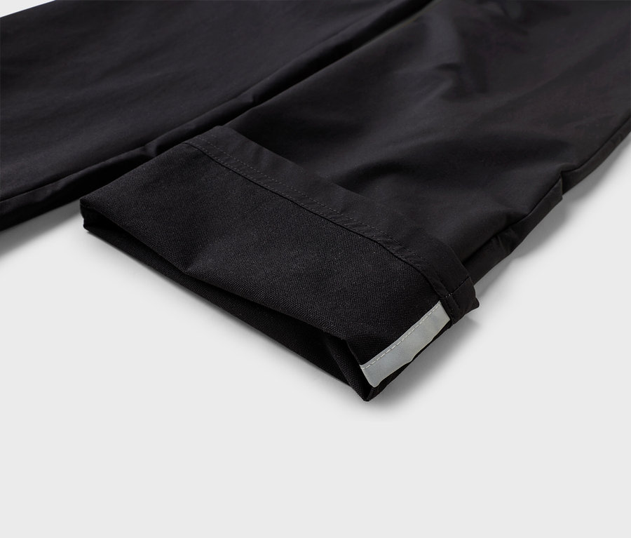 Detailaufnahme einer umgeschlagenen schwarzen Stoffhose mit reflektierendem Streifen am Saum.