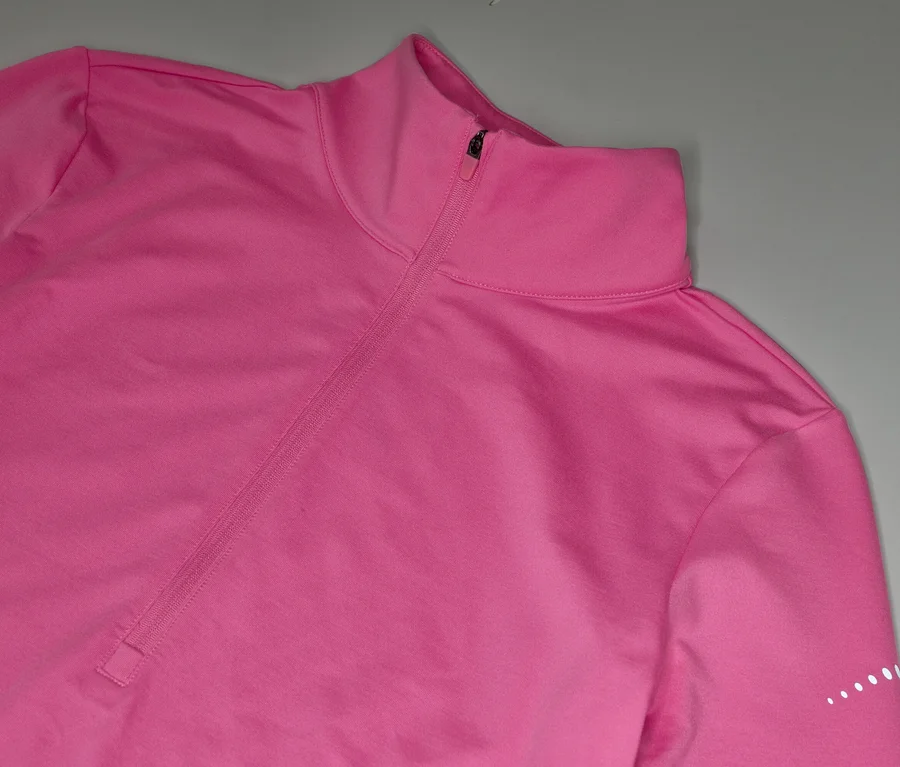 Pinkes, langärmeliges Sportoberteil mit kurzem Reißverschluss am Kragen und weißen Punkten am Ärmel.