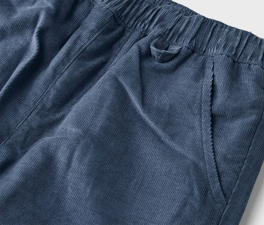 Nahaufnahme einer marineblauen Kordhose mit elastischem Bund und einer Seitentasche.