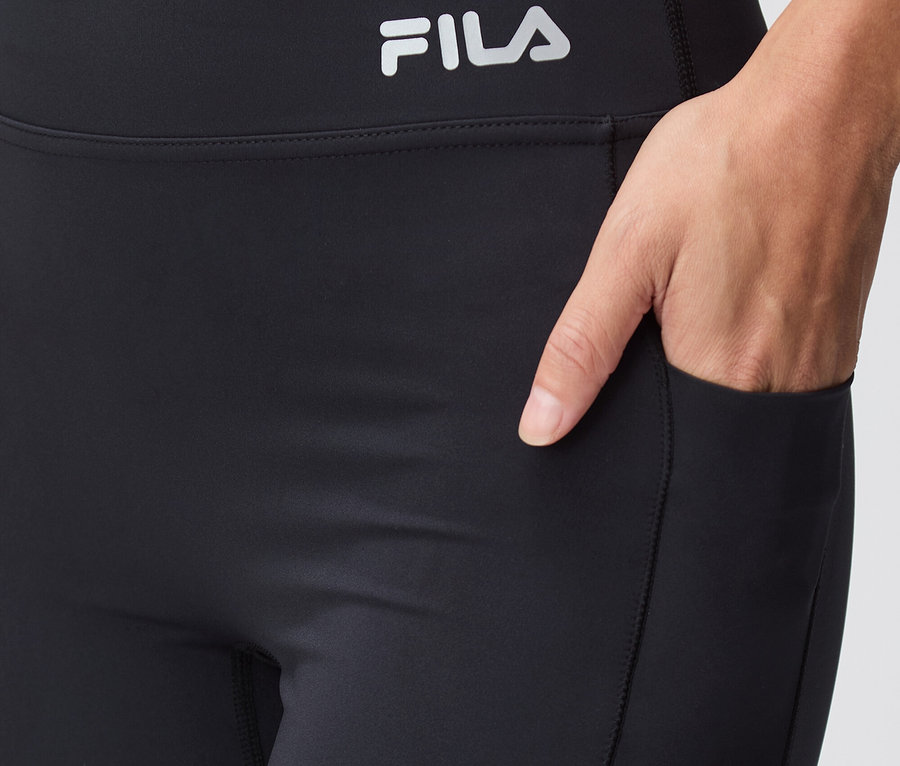 Nahaufnahme von schwarzen Fila-Leggings mit einer Hand in der Tasche.