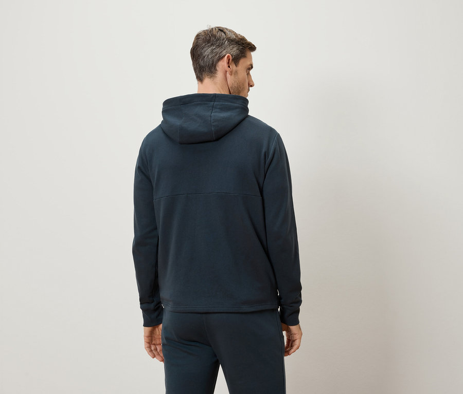 Mann von hinten, trägt einen dunkelblauen Hoodie und Trainingshose.