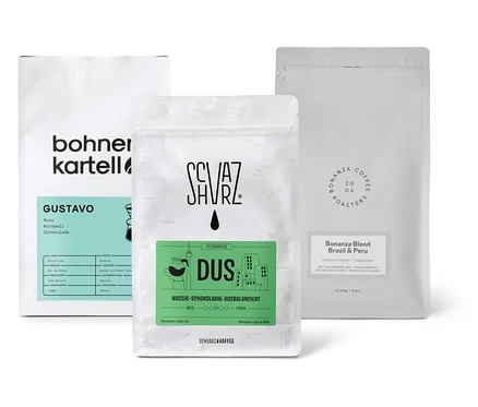 Drei Packungen Filterkaffee Probierset "Dreierpack schokoladig" mit ganzen Bohnen stehen auf einer weißen Oberfläche.