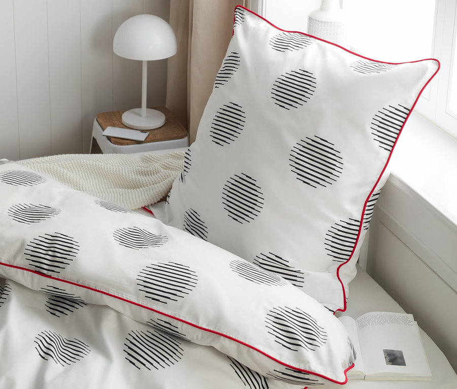 Detailansicht von Perkal-Bettwäsche in Normalgröße, Doppelgröße und Übergröße mit schwarzen Kreisen und roter Bordüre.