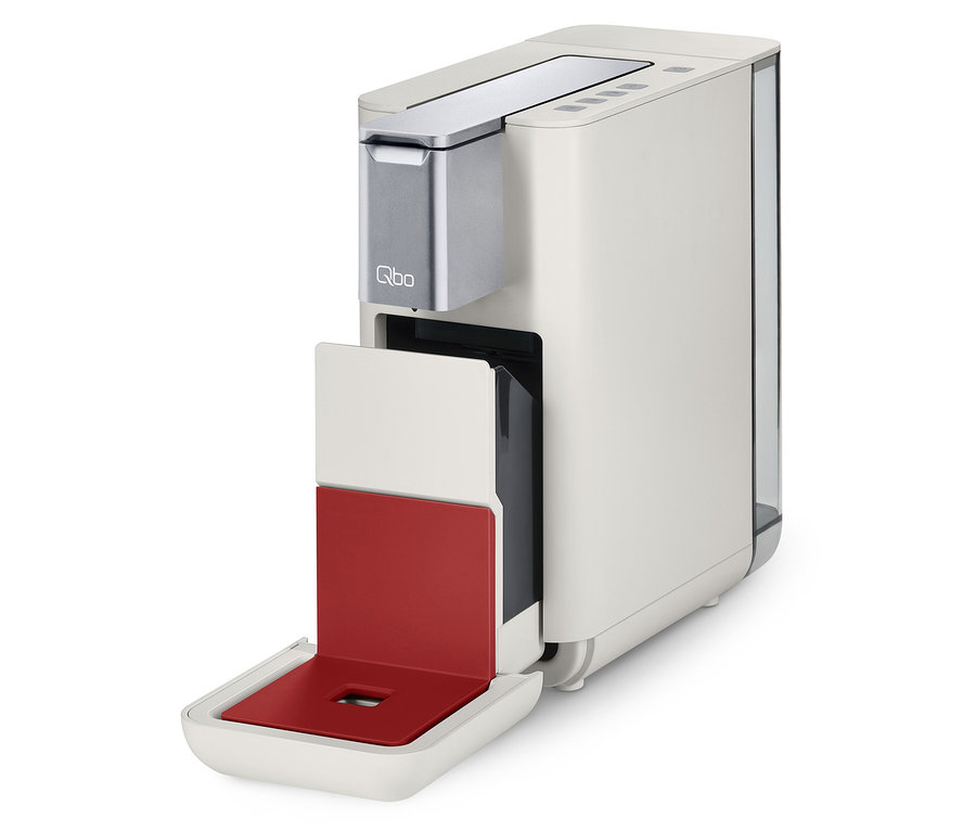 Eine Qbo ESSENTIAL Bright Coral Kaffeemaschine mit geöffnetem Kapselbehälter.