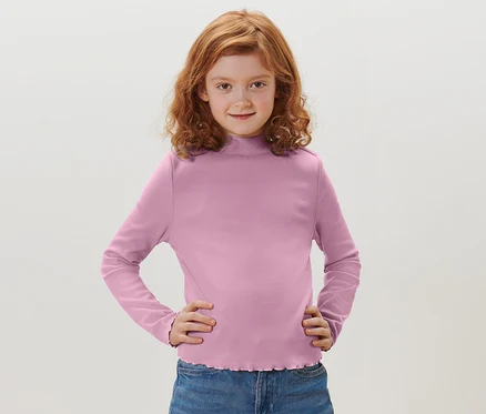 Mädchen mit roten Haaren posiert in einem violetten Kinder-Langarmshirt.