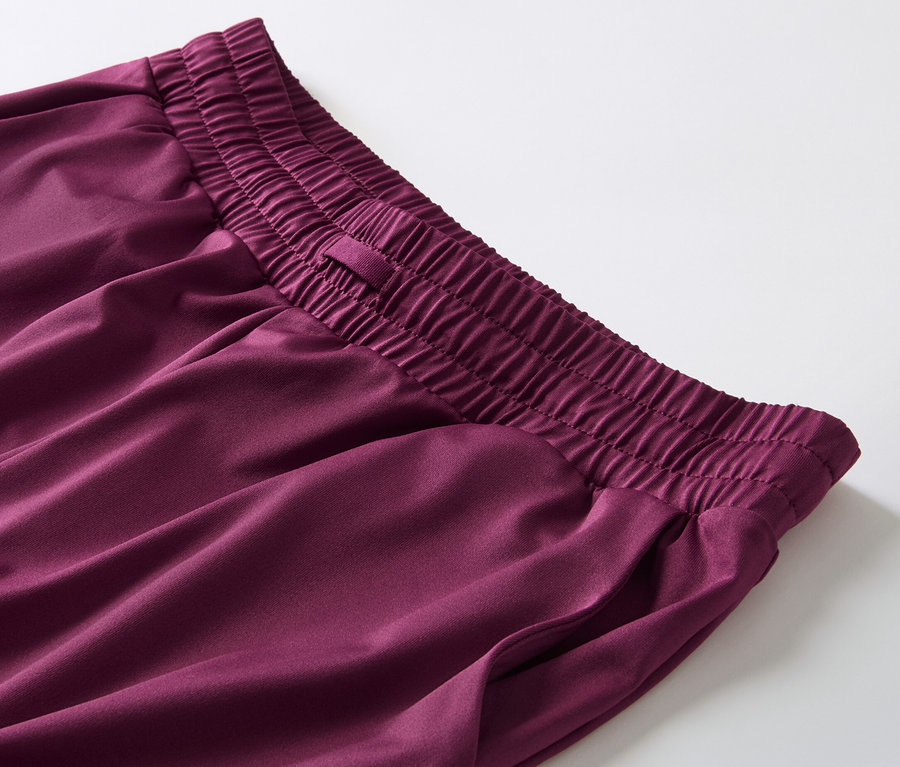 Detail einer Trainingshose in Beere mit elastischem Bund und Tasche.