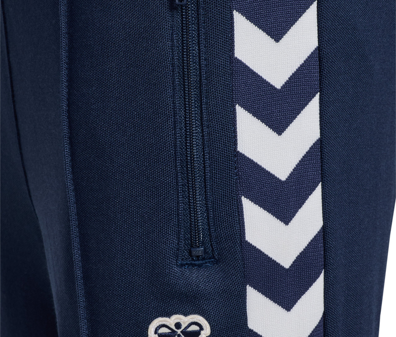 Detailansicht einer marineblauen HUMMEL HMLJR Archive Regular Poly Pants mit Reißverschluss und weißem Logo.