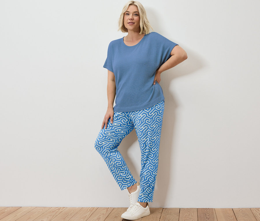 Blonde Frau posiert in blau bedruckter Jerseyhose und blauem, strukturiertem Shirt.