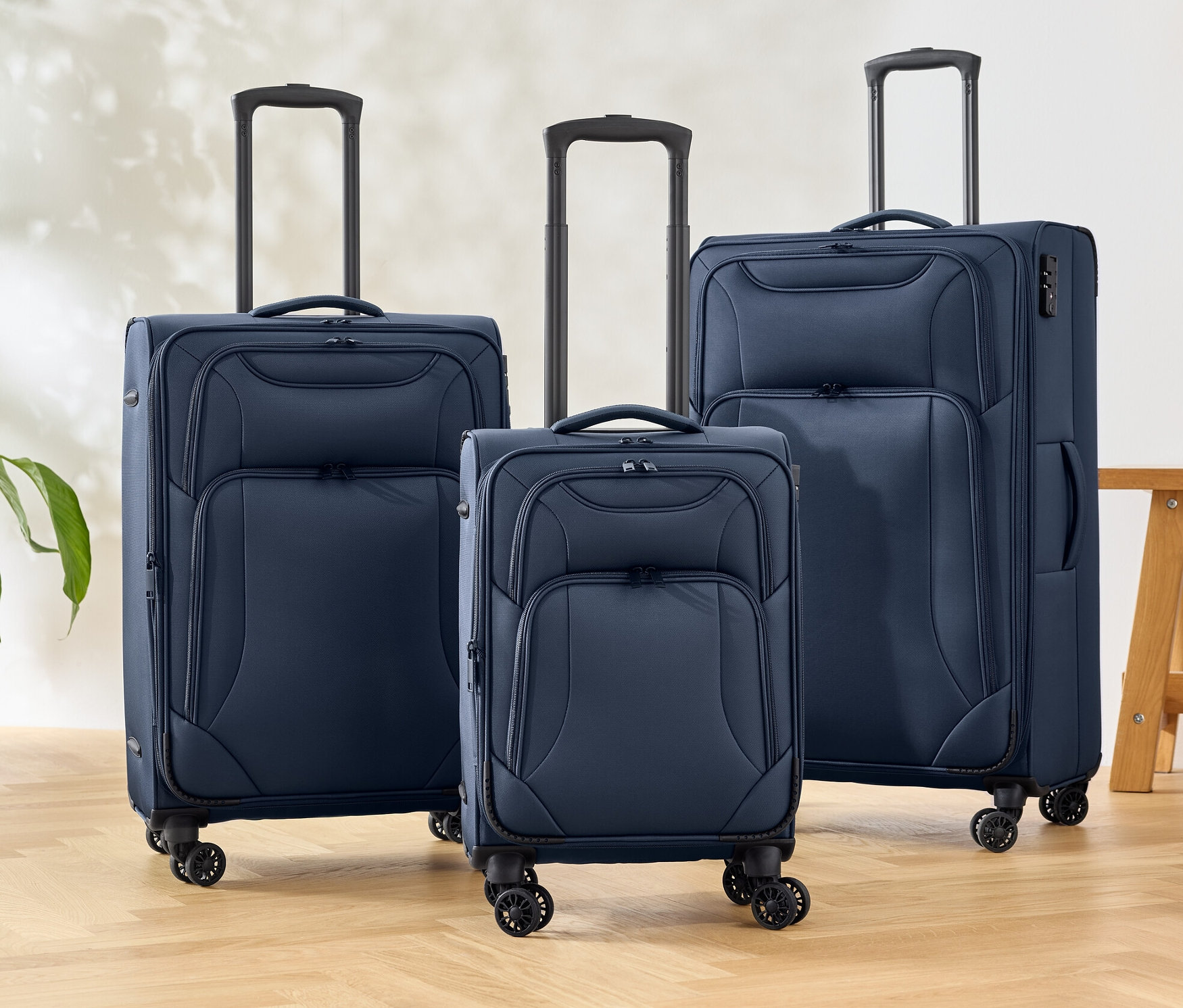 Drei blaue Textilkoffer stehen auf einem Boden.