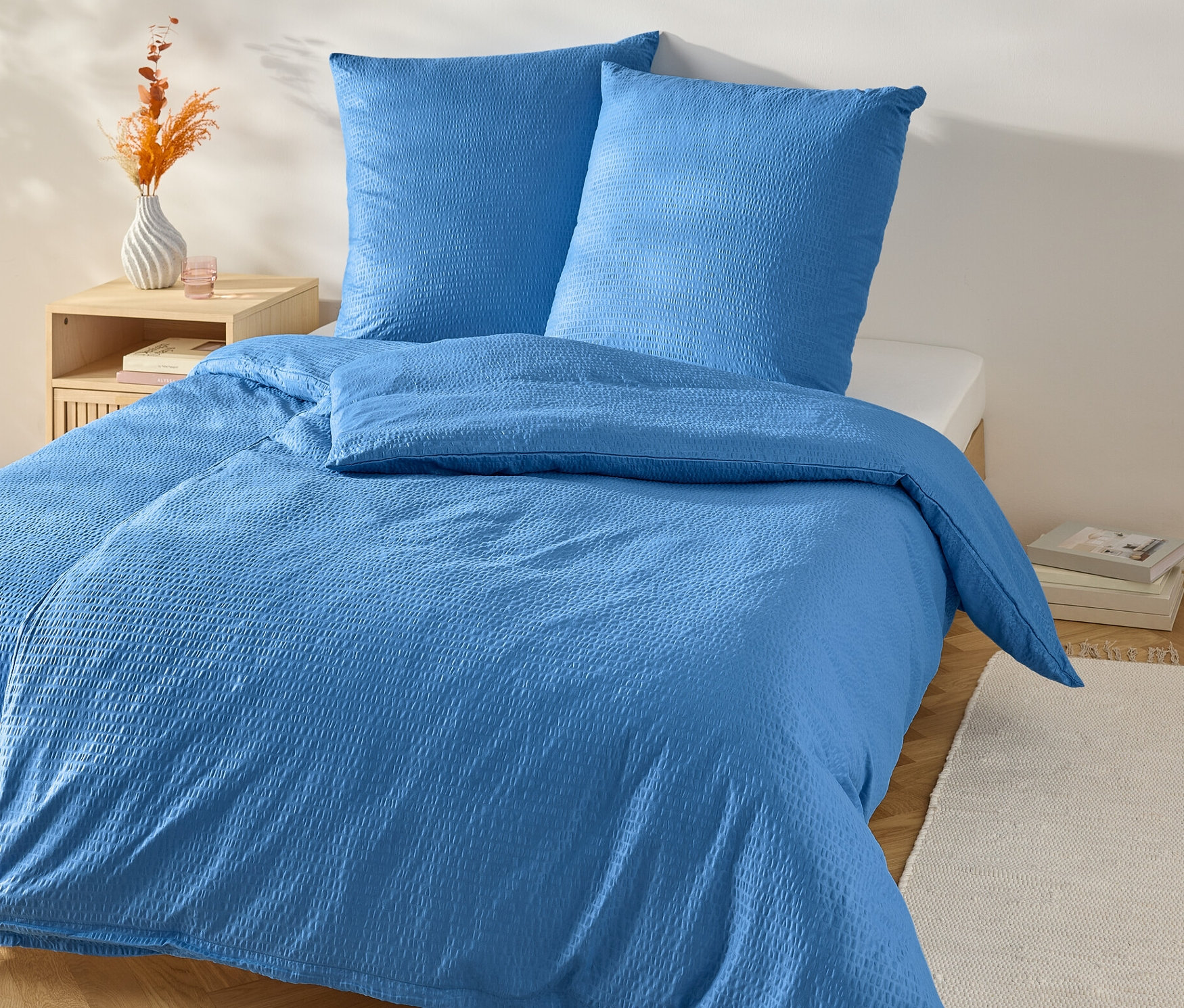 Blaue Seersucker-Bettwäsche Normalgröße auf einem Bett mit Nachttisch.