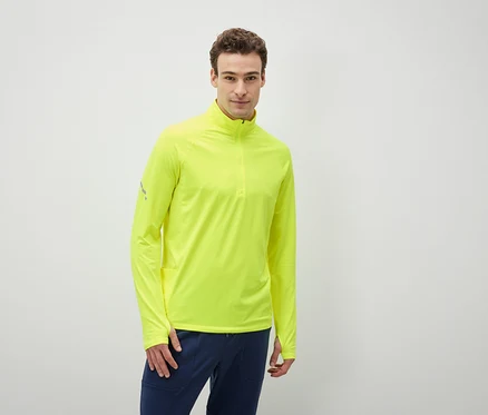 Mann trägt ein neongelbes Langarmshirt und dunkelblaue Hosen.