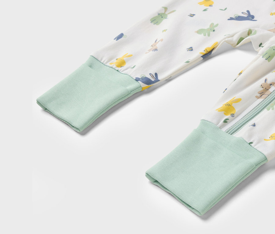 Detailaufnahme eines Kinderoveralls mit Hasenmuster und hellgrünen Bündchen.