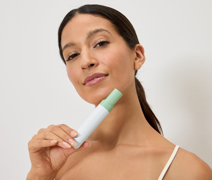 Frau hält eine weiss-grüne Flasche vor ihr Gesicht.