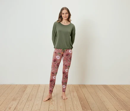 Frau steht und trägt ein grünes Langarmshirt und Leggings mit Blumenmuster.