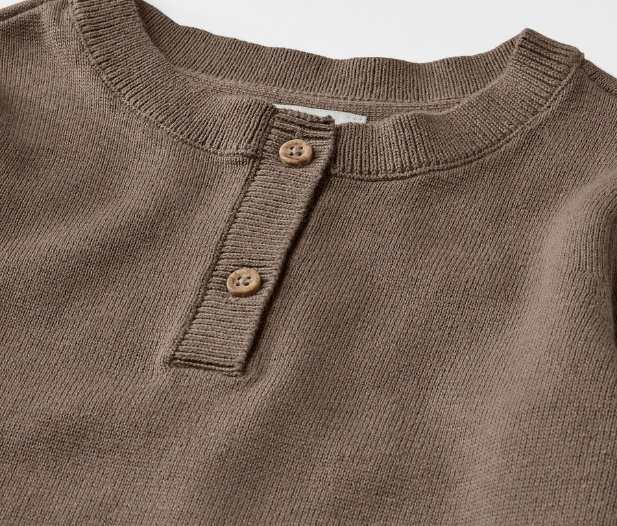 Detailaufnahme eines braunen Kinder-Henley-Strickpullovers mit Knöpfen.