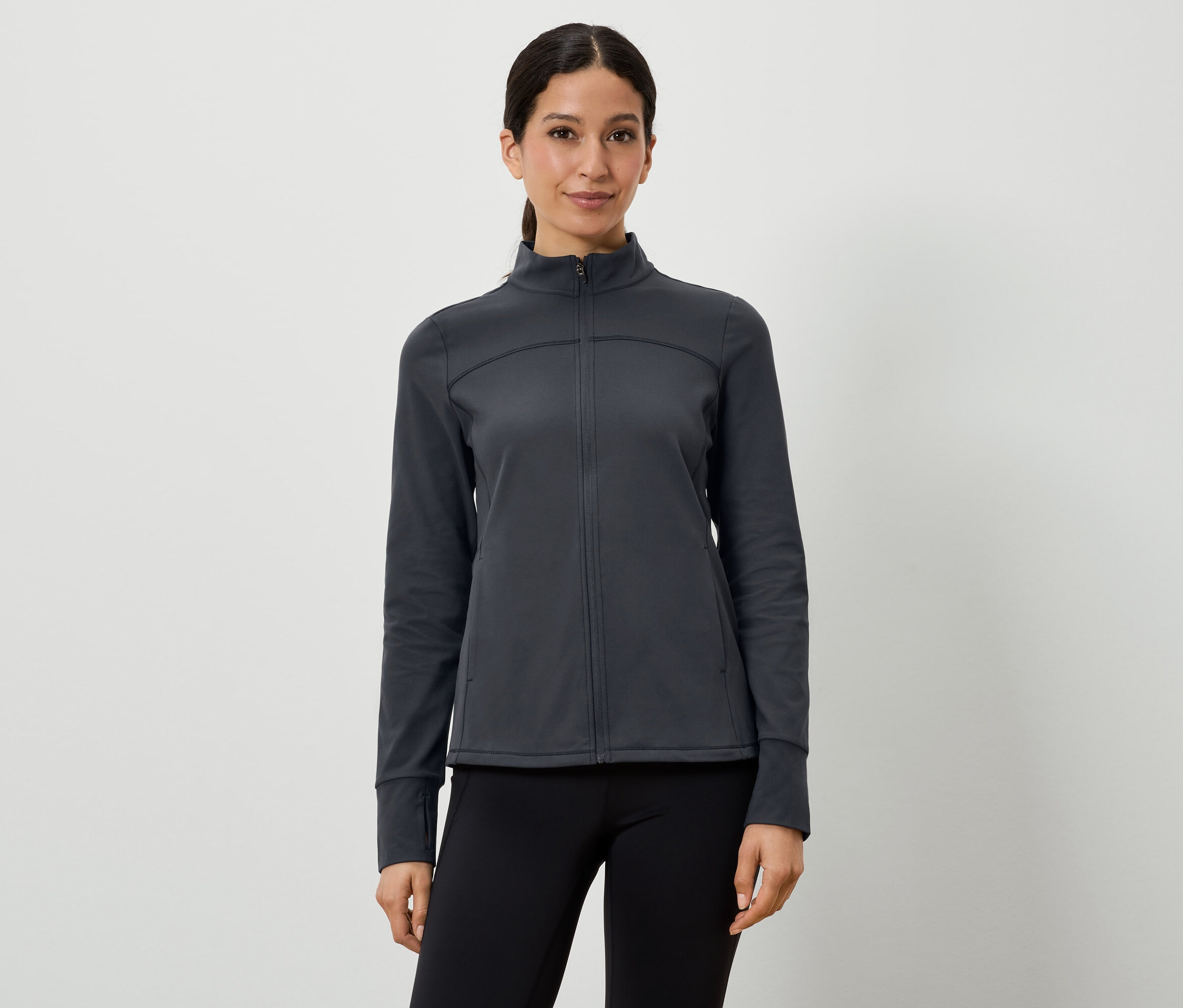 Frau trägt eine dunkelgraue Sportjacke und schwarze Leggings.