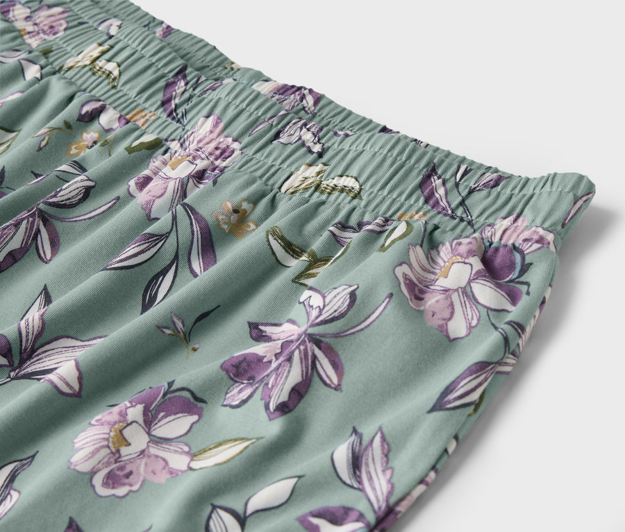 Detail einer hellgrünen Hose mit lila Blumenmuster und elastischem Bund.
