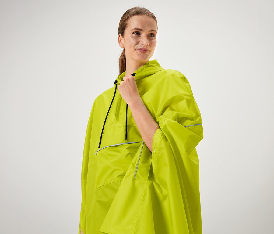 Frau hält den Kragen eines neongrünen Ponchos.