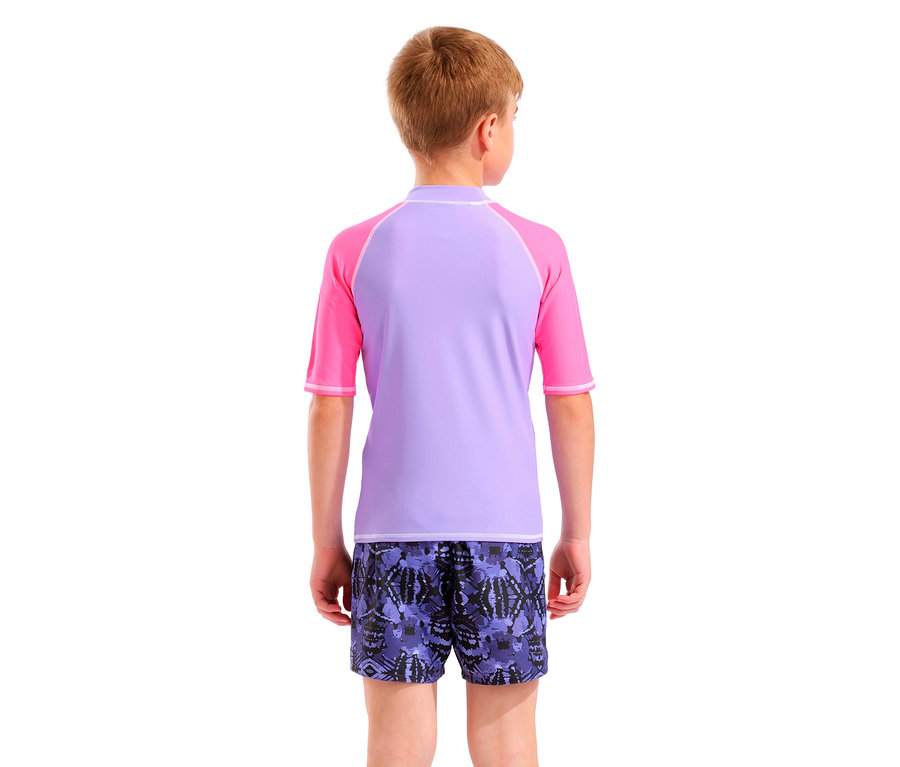 Rückansicht eines Kindes mit blonden Haaren, das ein lila-pinkes Rashguard-Shirt und lilafarbene Badeshorts mit Muster trägt.