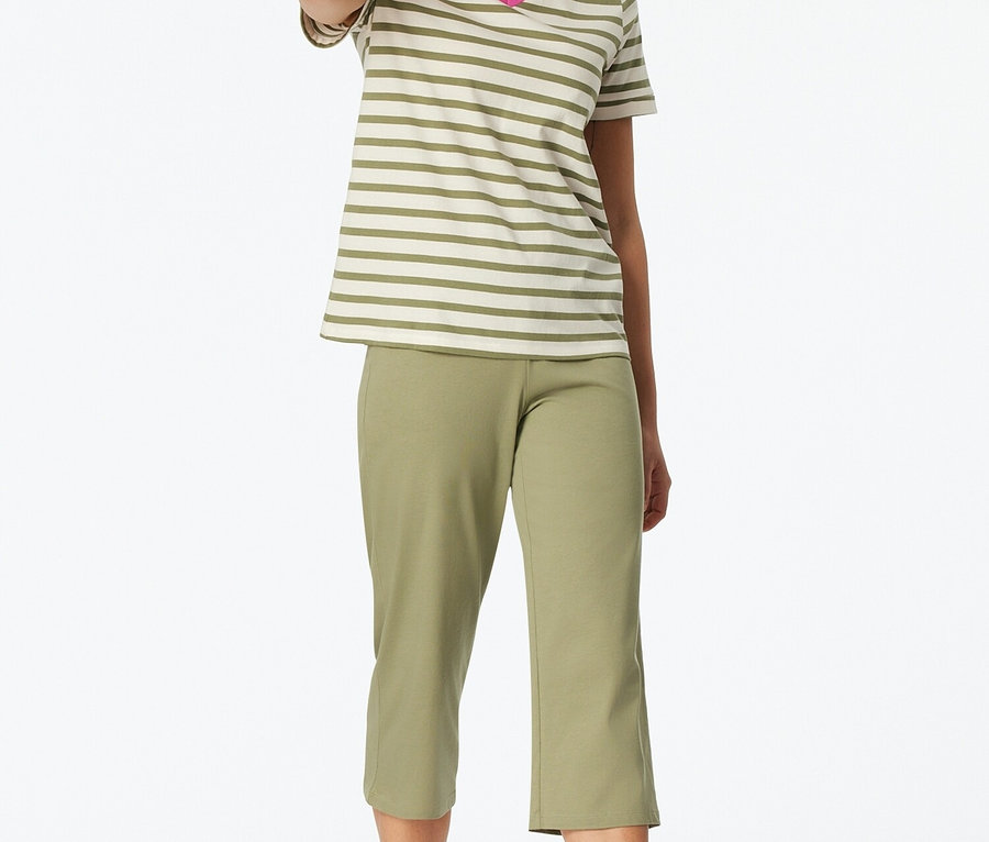 Frau steht barfuß und trägt ein gestreiftes T-Shirt mit V-Ausschnitt und eine grüne Caprihose.