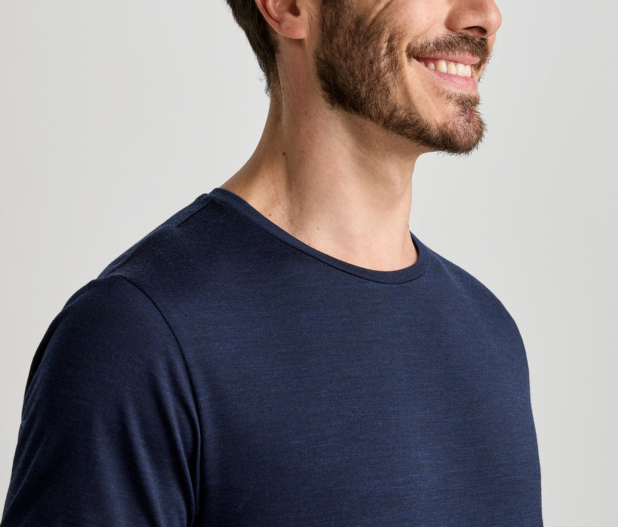 Nahaufnahme eines lächelnden Mannes mit Bart, der ein dunkelblaues Langarmshirt trägt.