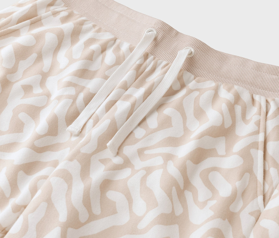 Nahaufnahme einer beigen Hose mit weißem Muster und Kordelzug.