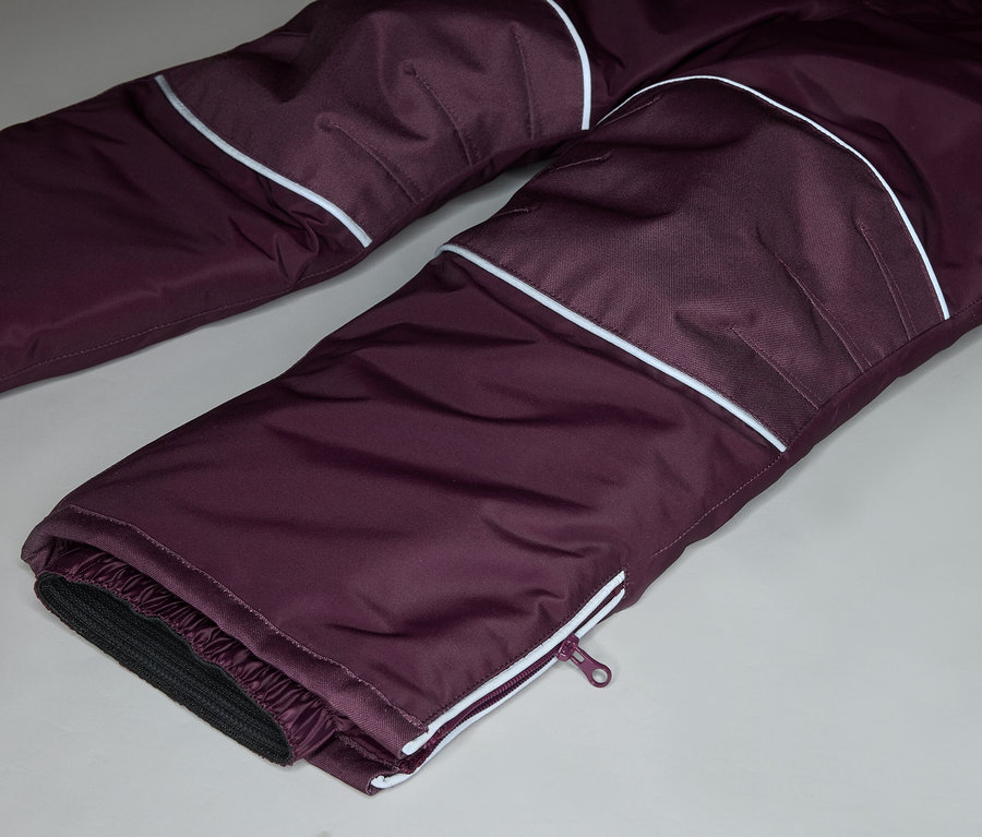 Nahaufnahme einer auberginefarbenen Hose mit weißen Akzenten und Reißverschlussdetail am Beinabschluss.