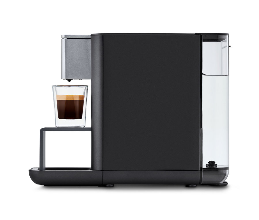 Qbo ESSENTIAL Dark Stone Kaffeemaschine mit einer Tasse Kaffee.