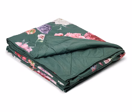 Gefaltete, grüne Steppdecke mit Blumenmuster in Rosa, Lila und Weiß.