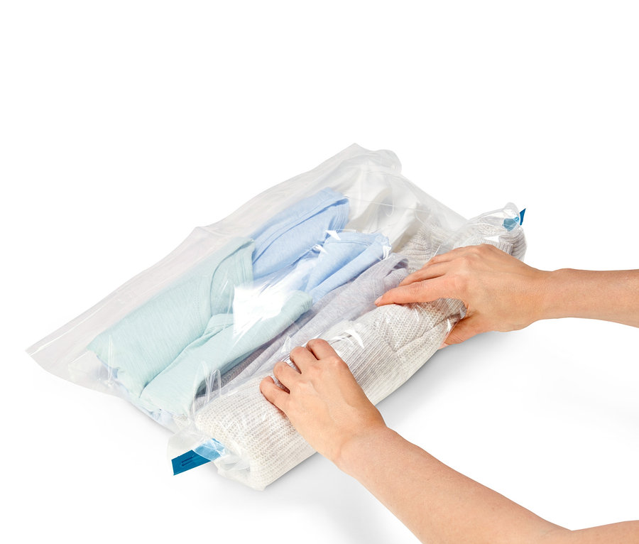 Eine Person packt einen Pullover in einen der 3 Vakuum-Reisebeutel.