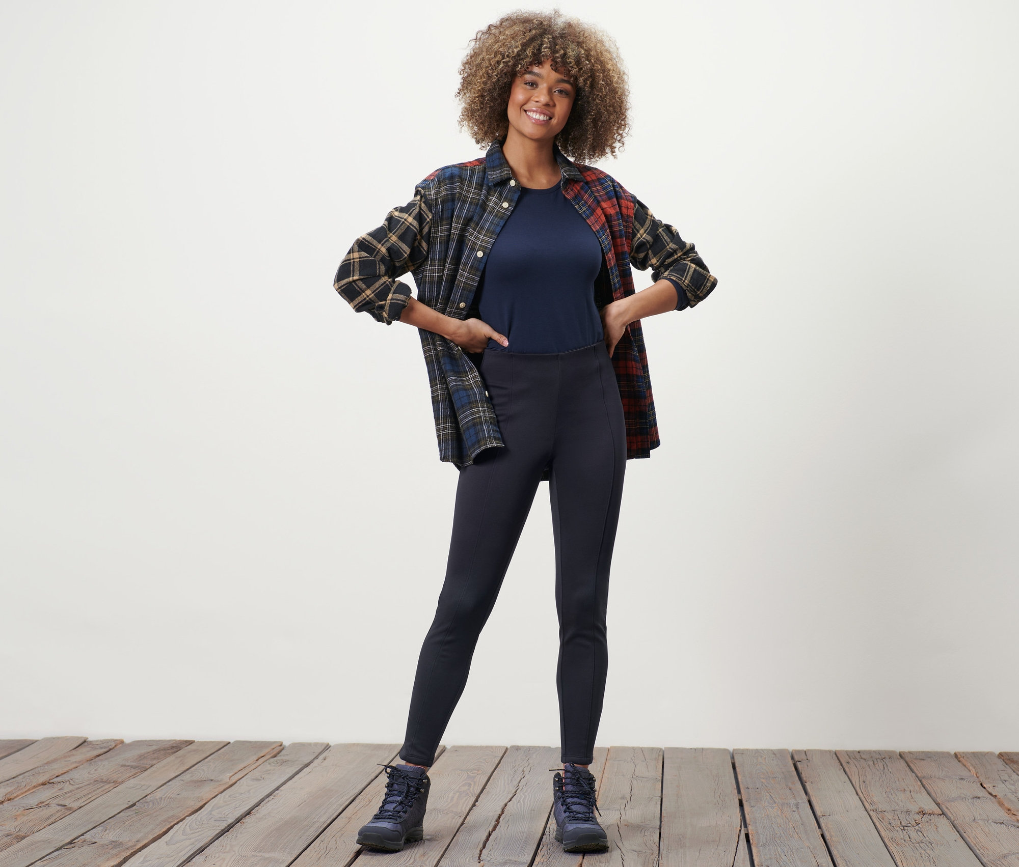 Frau posiert in Thermotights, T-Shirt und kariertem Hemd.