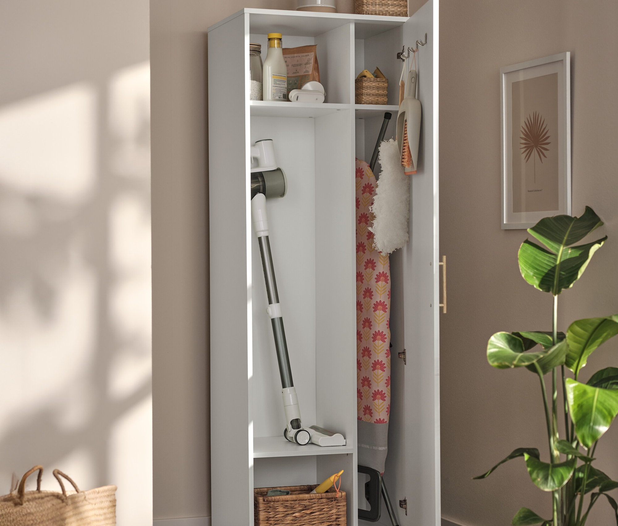 Offener, weißer Universalschrank mit Staubsauger, Bügelbrett und Körben im Innenraum.