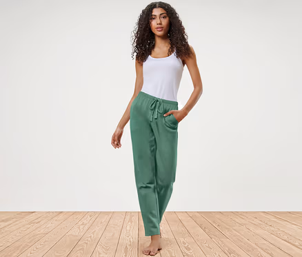 Frau posiert in grüner Loungewear-Hose und weißem Top.
