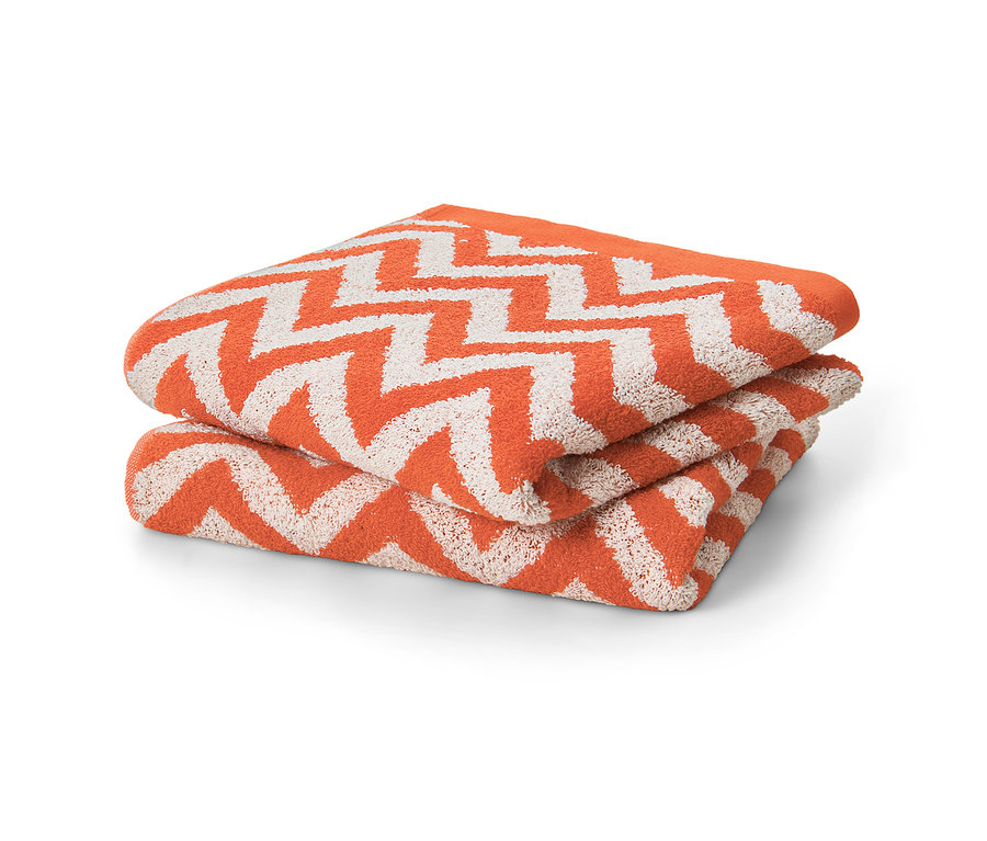 Zwei orangefarbene Jacquard-Handtücher liegen gefaltet übereinander.
