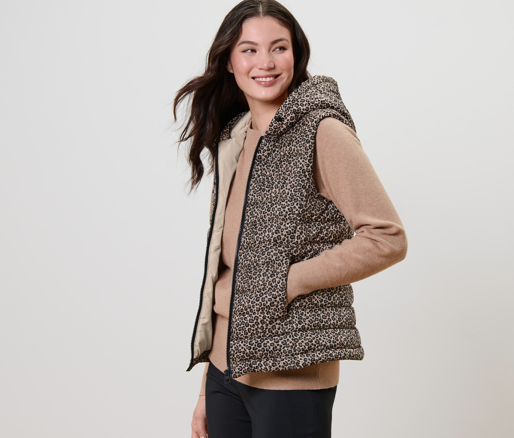 Frau posiert in bedruckter Steppweste mit Kapuze.