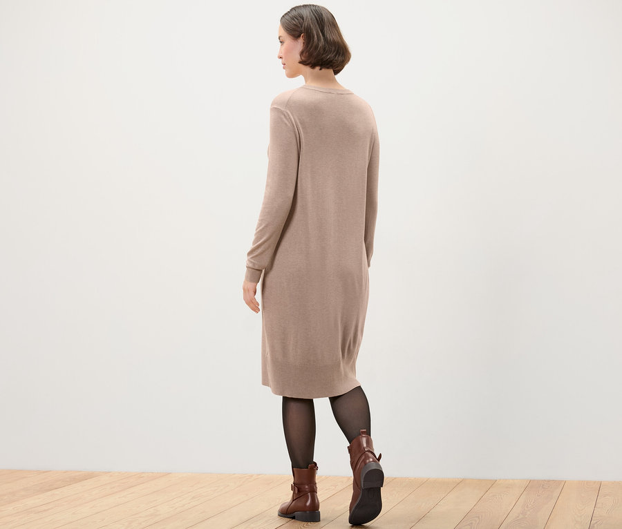 Frau trägt Feinstrickkleid, schwarze Strumpfhose und braune Stiefel.