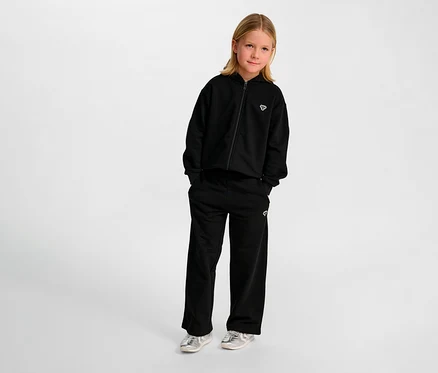 Mädchen trägt schwarze HUMMEL HMLJR Loose WL Trainingshose und Kapuzenjacke.