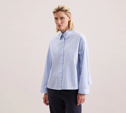 Frau trägt eine Seidensticker Oversize-Hemdbluse mit blauen Streifen.