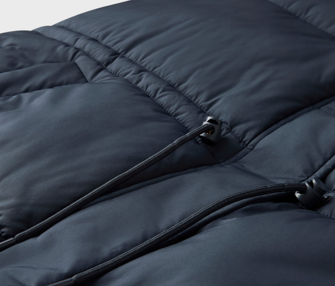 Detailaufnahme einer marineblauen Steppjacke mit Kordelzug.