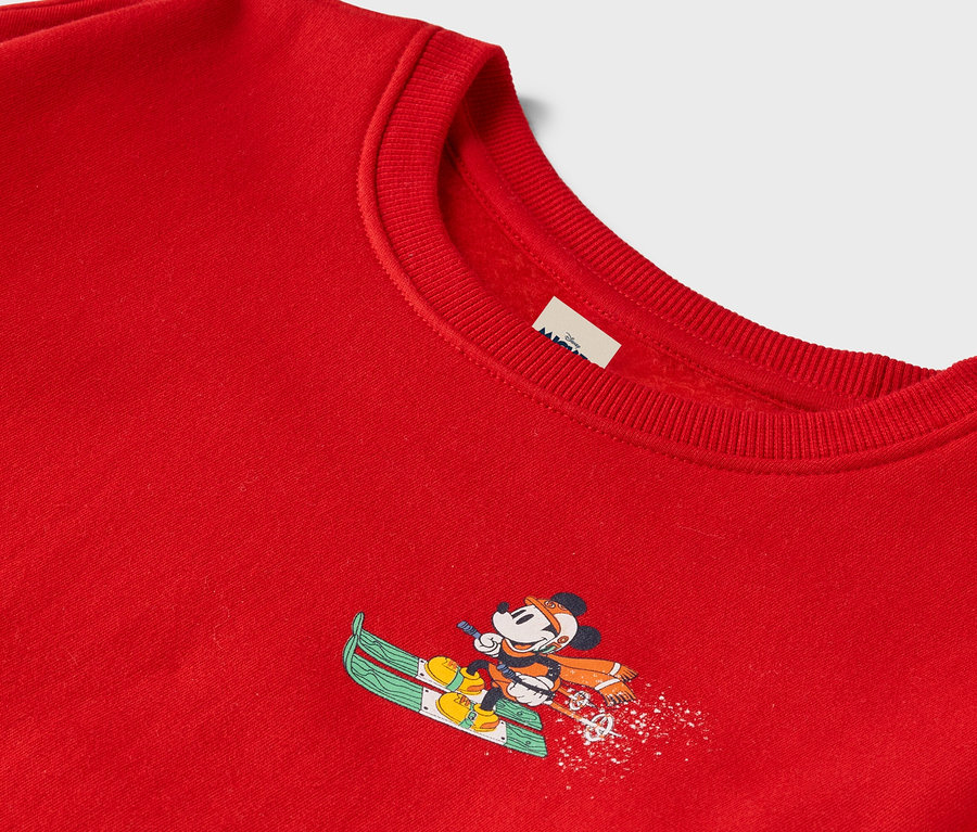 Roter Pullover mit Micky Maus auf Skiern.