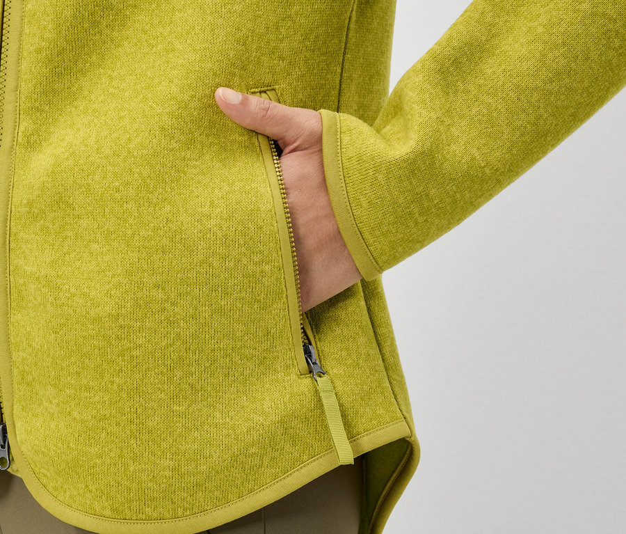 Eine Hand steckt in der Tasche einer gelben Fleecejacke.