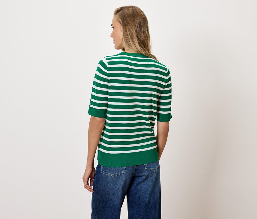 Eine Frau von hinten trägt ein grün-weiß gestreiftes T-Shirt und blaue Jeans.