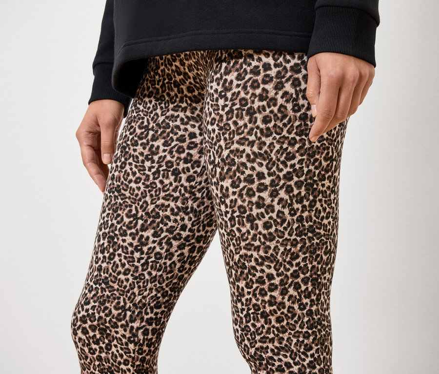 Unbekannte Person trägt ein schwarzes Oberteil und Leggings mit Tiermuster.