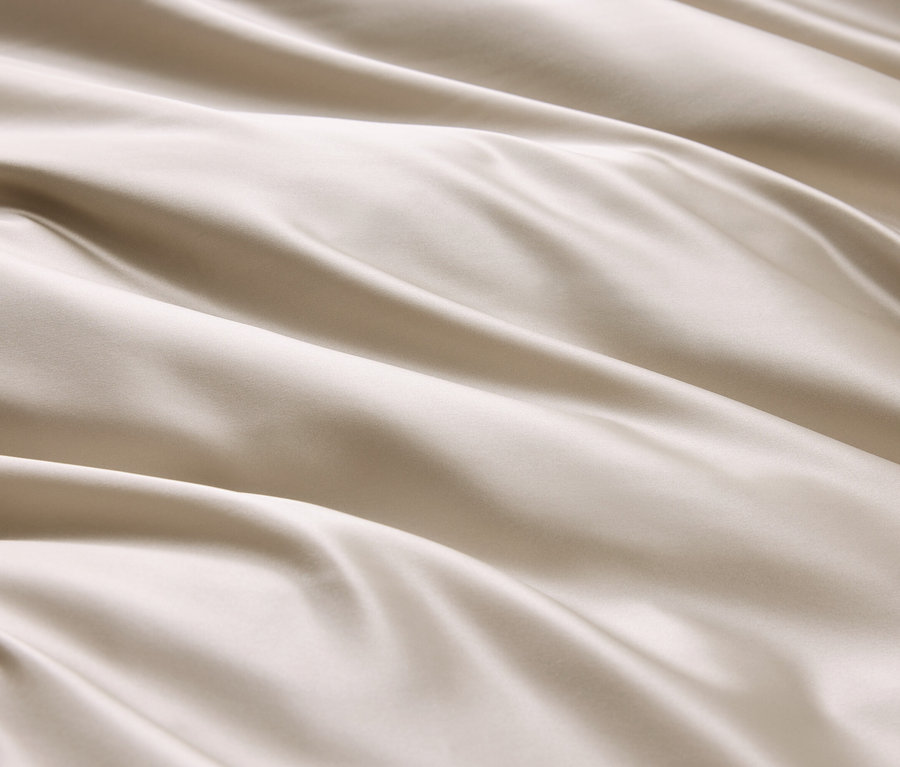 Detailaufnahme eines cremefarbenen Stoffes mit Wellen und Falten.