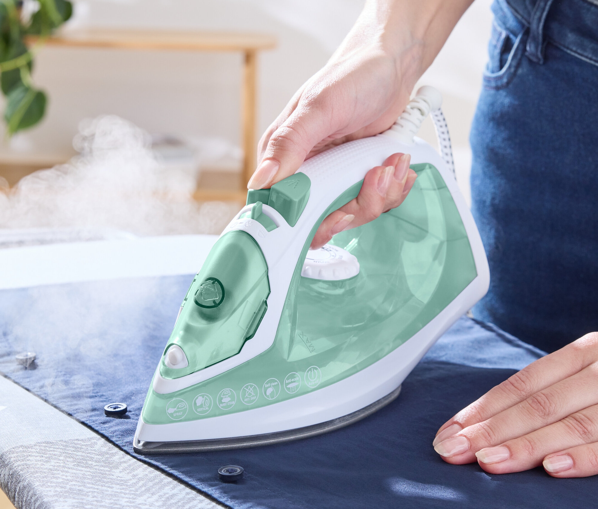 Eine Frau bügelt ein Hemd mit einem Dampfbügeleisen.