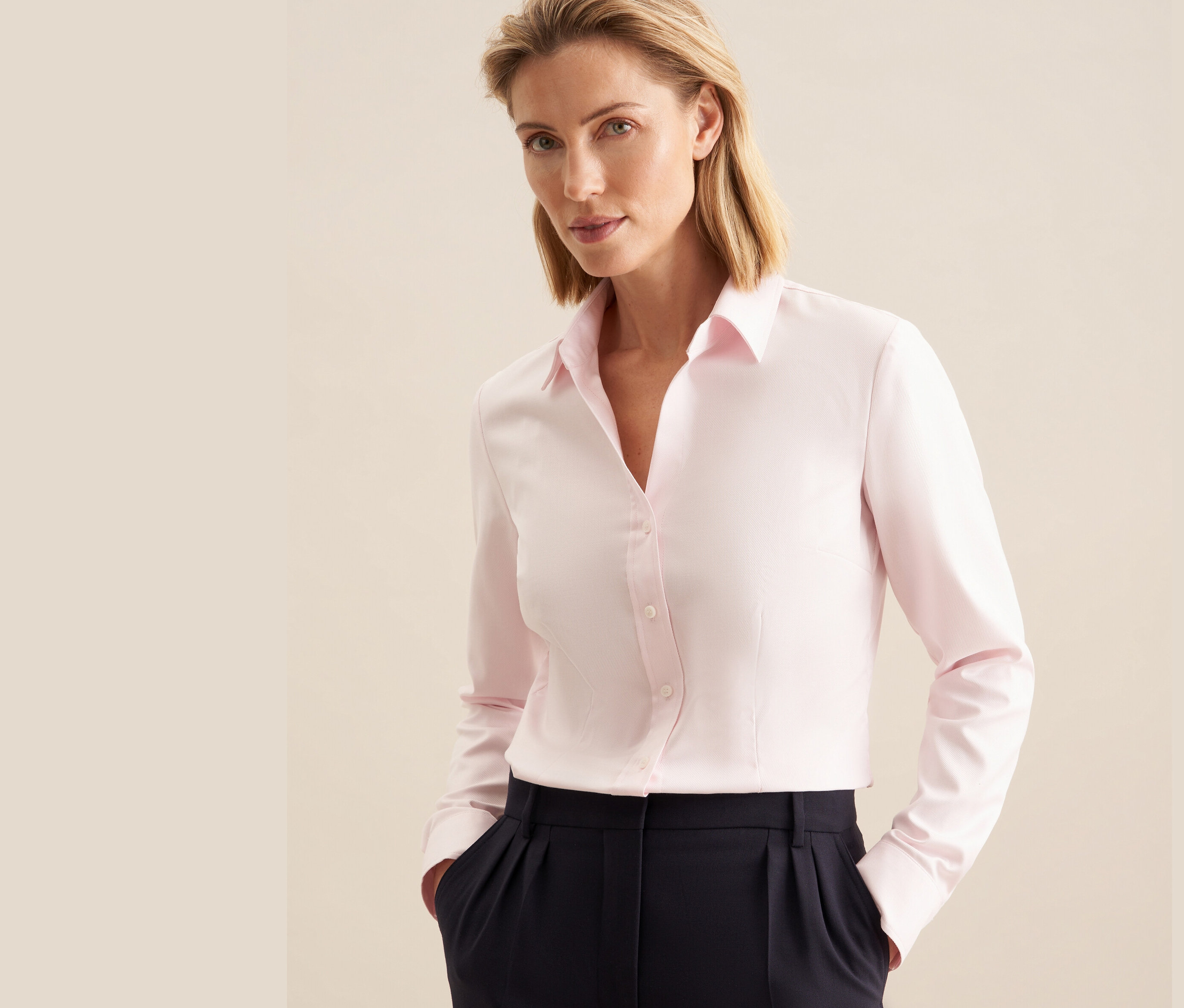 Frau trägt eine roséfarbene Seidensticker Twillbluse und eine marineblaue Hose.