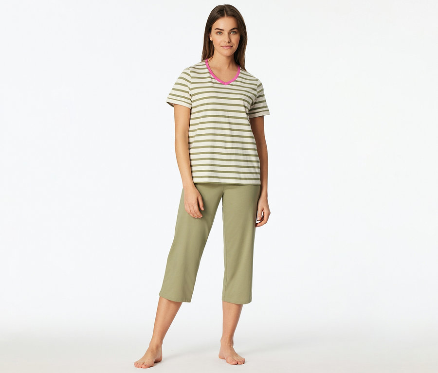 Eine Frau steht barfuß und trägt ein SCHIESSER 3/4-Pyjama-Set. Das Oberteil ist gestreift in Grün und Weiß mit pinkem V-Ausschnitt, die Hose ist eine grüne Caprihose.