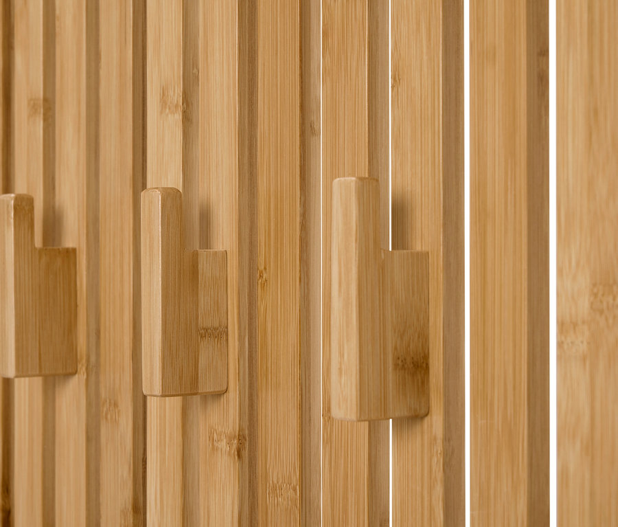 Nahaufnahme von drei hölzernen Kleiderhaken an einer Wand aus vertikalen Holzpaneelen.