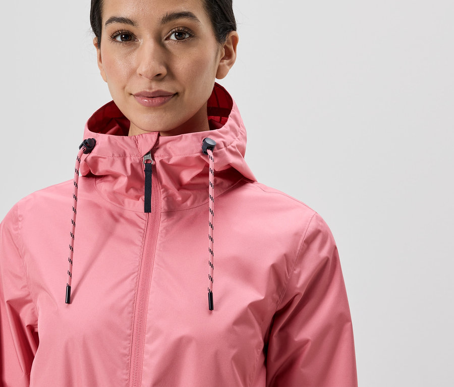 Frau mit Kapuze trägt eine pinke Jacke mit Reißverschluss und Kordelzug.