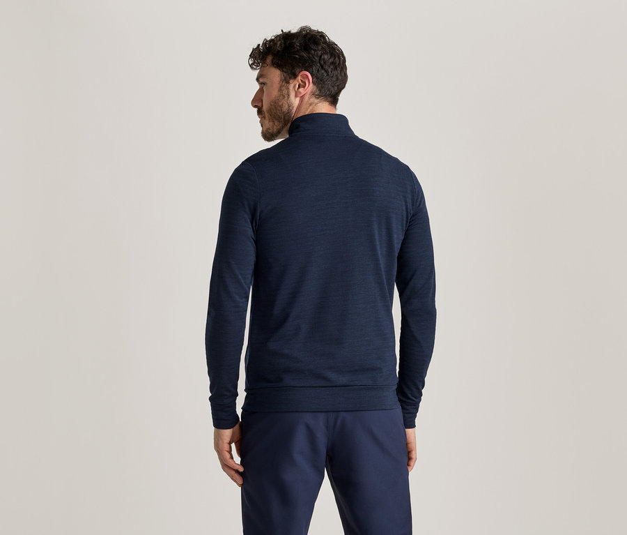 Von hinten ist ein Mann mit dunklen Haaren in einem marineblauen Langarmshirt und einer Hose zu sehen.
